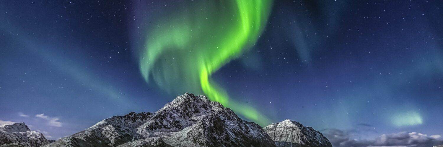 Green Aurora Borealis Over Snow Covered Mountain