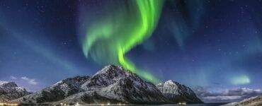 Green Aurora Borealis Over Snow Covered Mountain