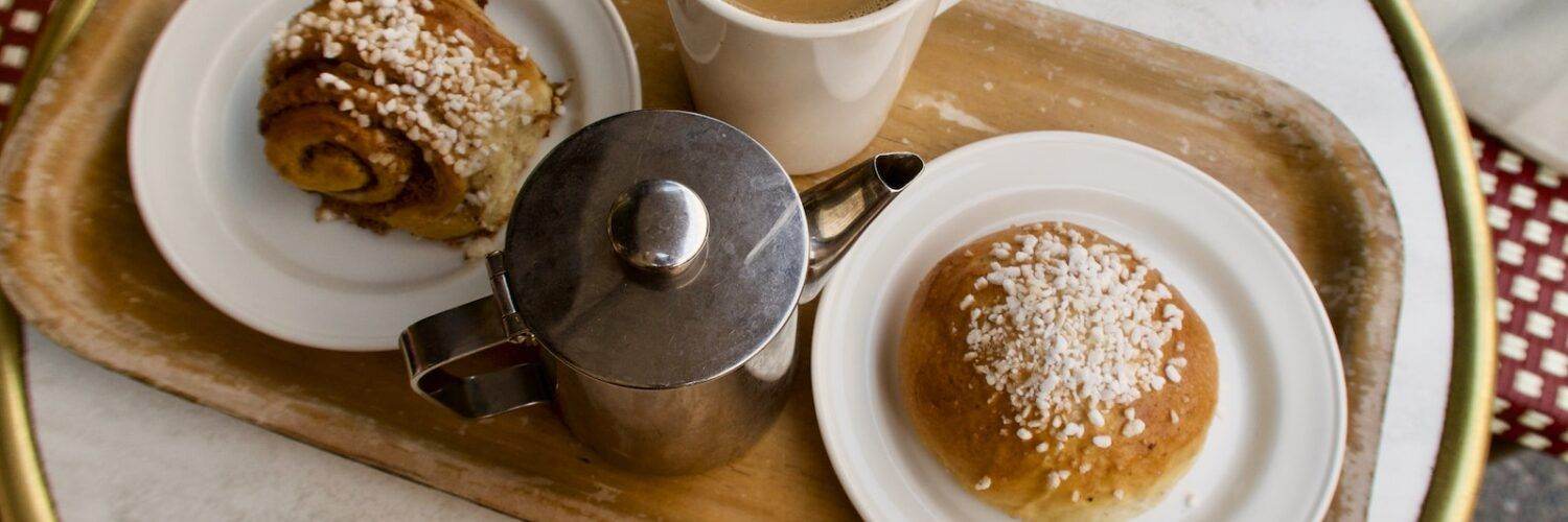 White Ceramic Mug With Coffee Beside Stainless Steel Teapot on Brown Wooden Tray