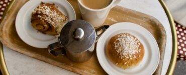 White Ceramic Mug With Coffee Beside Stainless Steel Teapot on Brown Wooden Tray