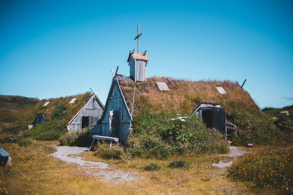 Old wooden church and house on meadow in countryside