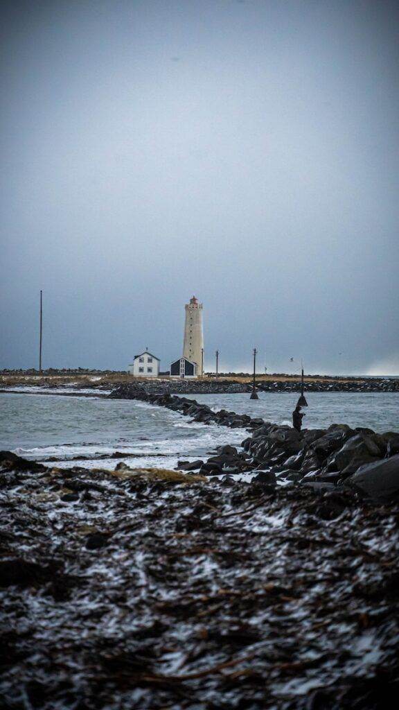 white lighthouse on rocky shore during daytime