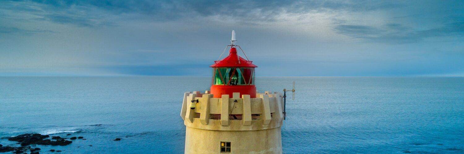 yellow and red lighthouse near body of water at daytime