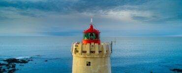 yellow and red lighthouse near body of water at daytime