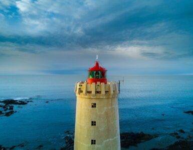 yellow and red lighthouse near body of water at daytime