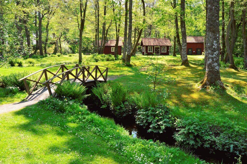 Brown Wooden House Near the Creek With a Bridge