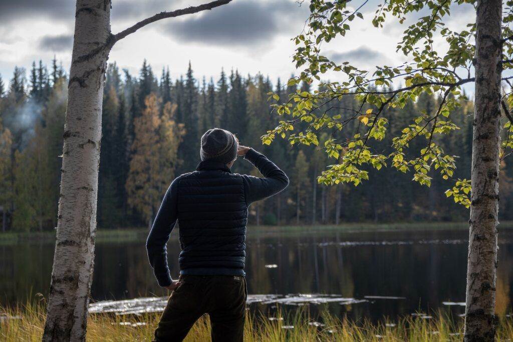 Man in Black and Gray Striped Long Sleeve Shirt Standing Near Body of Water