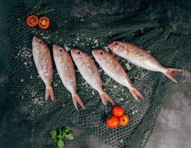 five fish between tomatoes on black net