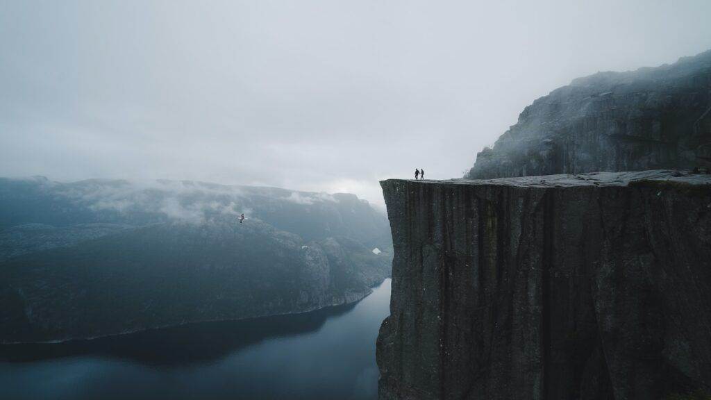 two people standing on edge of cliff at daytime