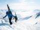 a man walking up a snow covered mountain holding skis