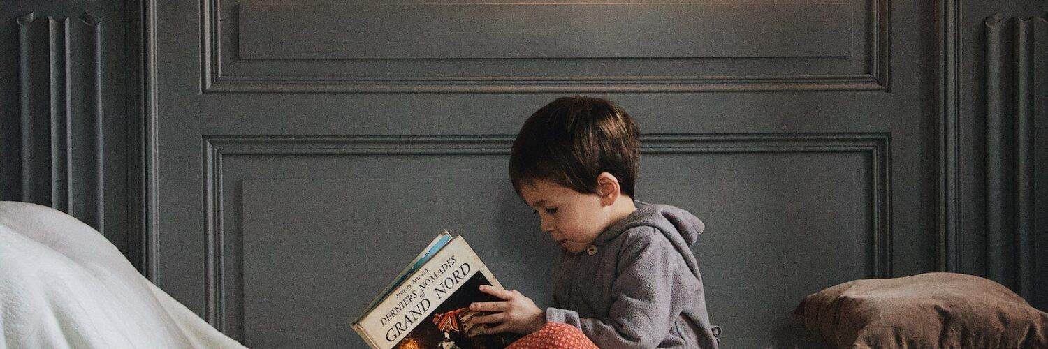 boy reading book on bed