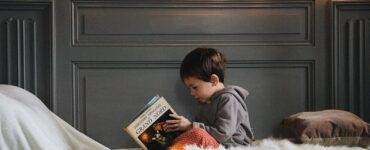 boy reading book on bed