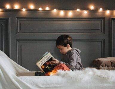 boy reading book on bed