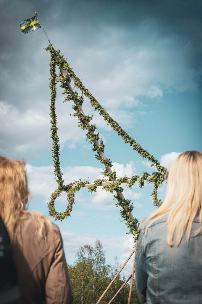 two women standing facing flag on pole