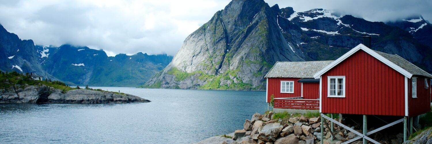 red and white wooden house in front of body of water