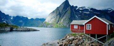 red and white wooden house in front of body of water