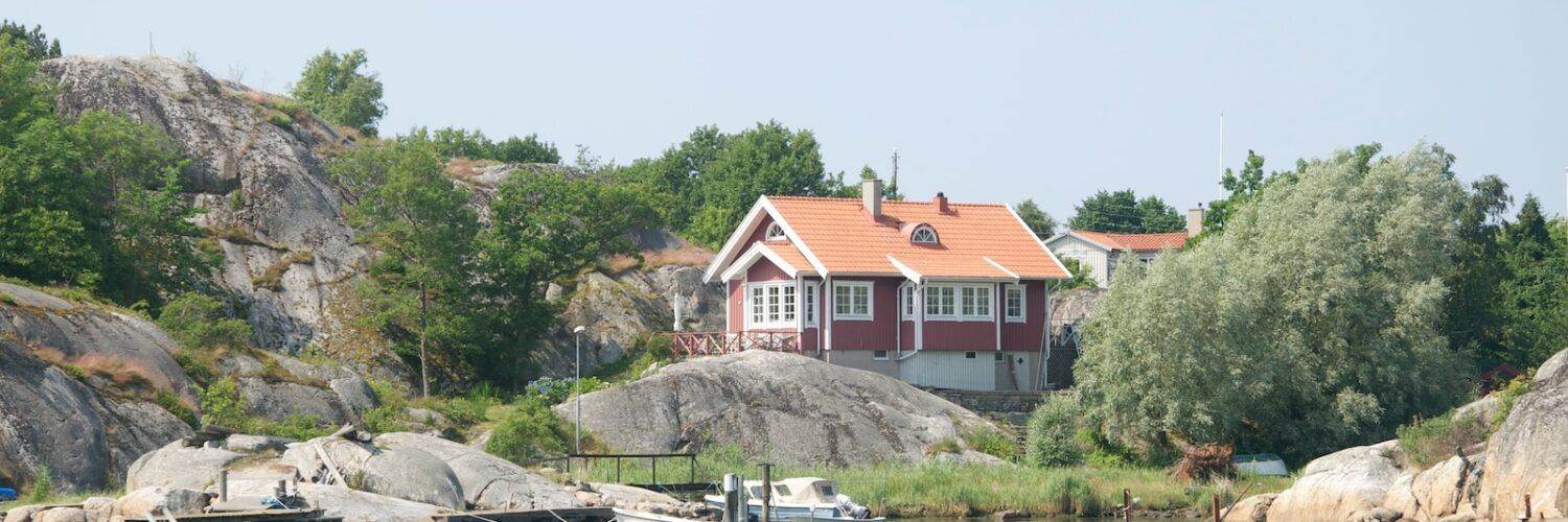 a house sitting on top of a hill next to a body of water