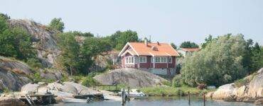 a house sitting on top of a hill next to a body of water