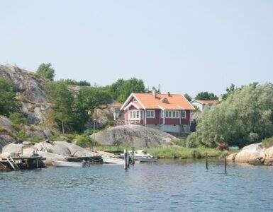 a house sitting on top of a hill next to a body of water